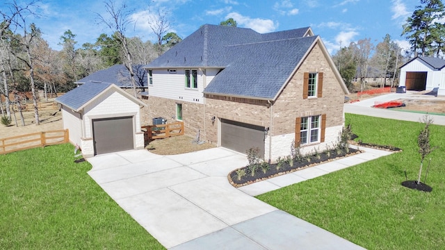 french country inspired facade featuring brick siding, a shingled roof, concrete driveway, fence, and a front lawn