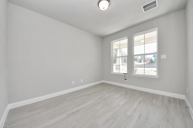 spare room featuring light wood-style flooring, visible vents, and baseboards