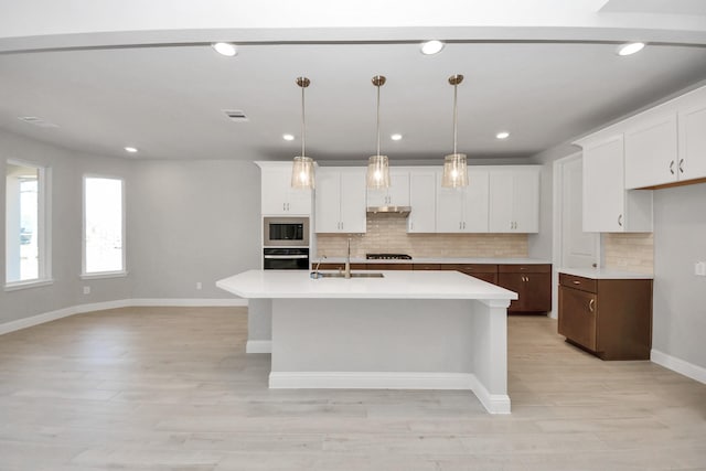 kitchen featuring light countertops, decorative backsplash, a sink, built in microwave, and oven