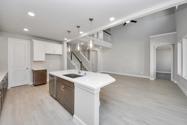 kitchen featuring light countertops, stainless steel dishwasher, a sink, and decorative backsplash