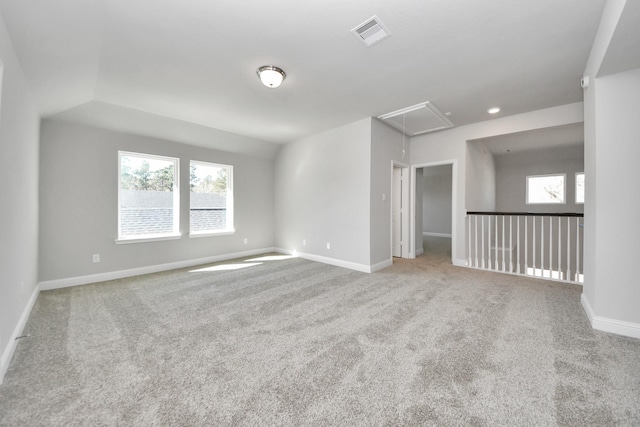 empty room featuring attic access, a healthy amount of sunlight, visible vents, and baseboards