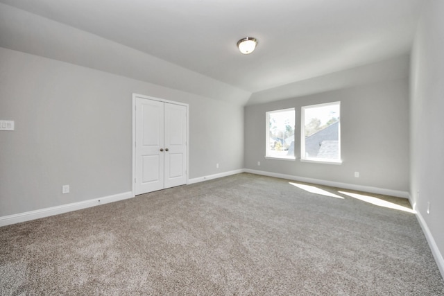 empty room featuring carpet, lofted ceiling, and baseboards