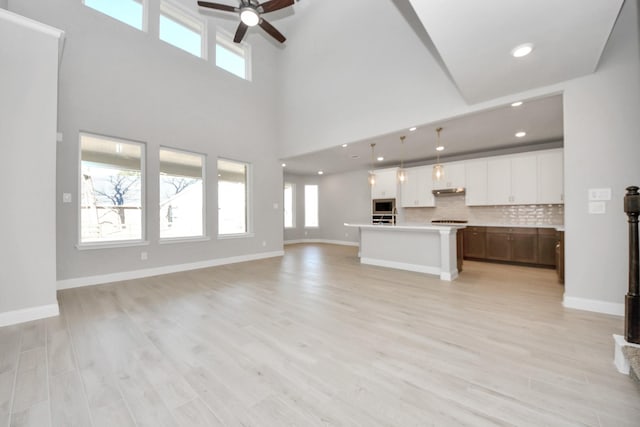 unfurnished living room with light wood-style flooring, baseboards, ceiling fan, and recessed lighting