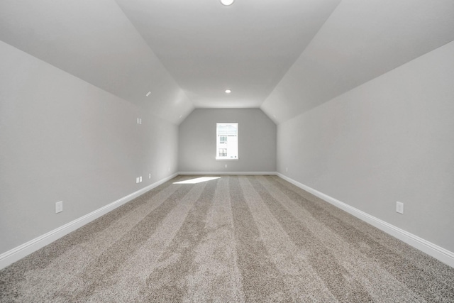 additional living space featuring lofted ceiling, light colored carpet, and baseboards