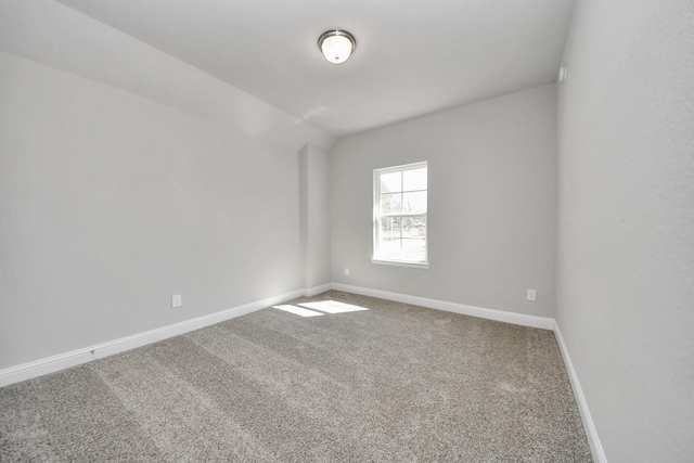 empty room with carpet floors, lofted ceiling, and baseboards