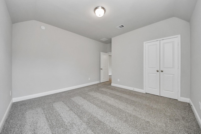 unfurnished bedroom with carpet, lofted ceiling, a closet, visible vents, and baseboards