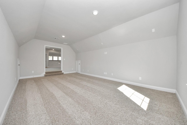 additional living space featuring recessed lighting, light carpet, visible vents, baseboards, and vaulted ceiling