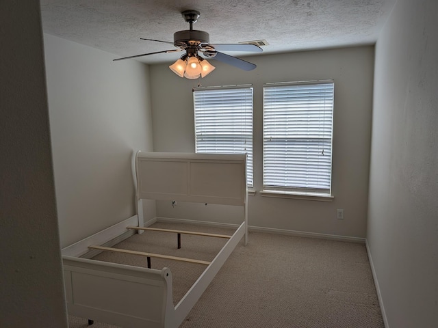 unfurnished bedroom featuring a textured ceiling, carpet floors, and ceiling fan