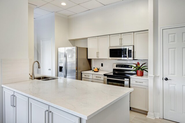 kitchen with light stone countertops, sink, kitchen peninsula, and stainless steel appliances