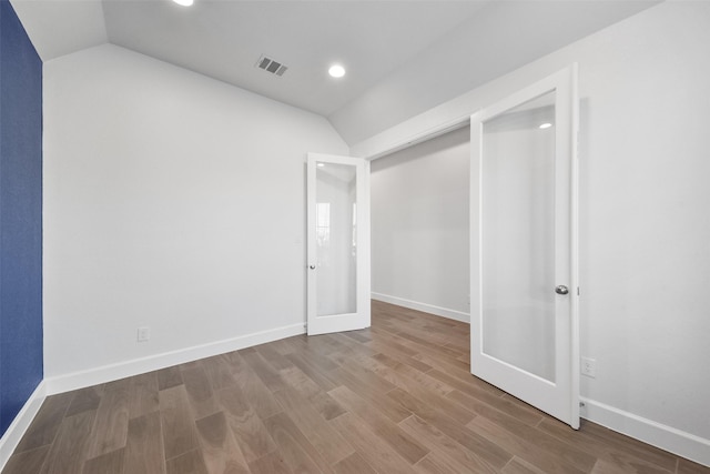 unfurnished bedroom with vaulted ceiling, a closet, and hardwood / wood-style flooring