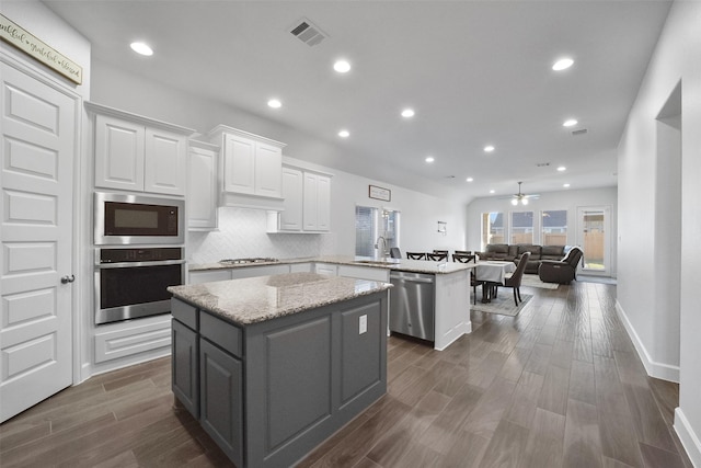 kitchen with white cabinetry, ceiling fan, kitchen peninsula, a kitchen island, and appliances with stainless steel finishes