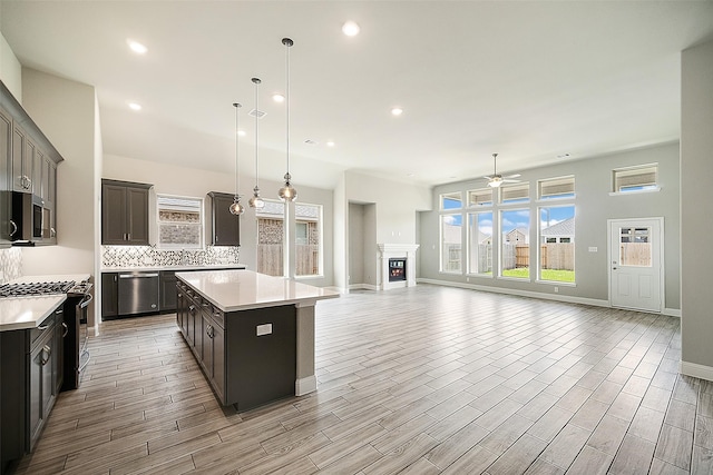 kitchen with tasteful backsplash, a center island, stainless steel appliances, light countertops, and wood finish floors