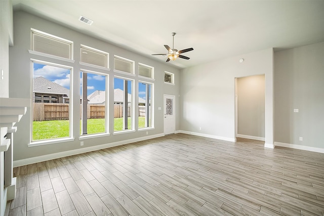 spare room with a ceiling fan, visible vents, baseboards, and wood finished floors