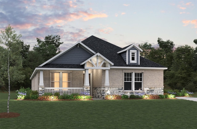 view of front of property with brick siding, a shingled roof, a porch, and a yard