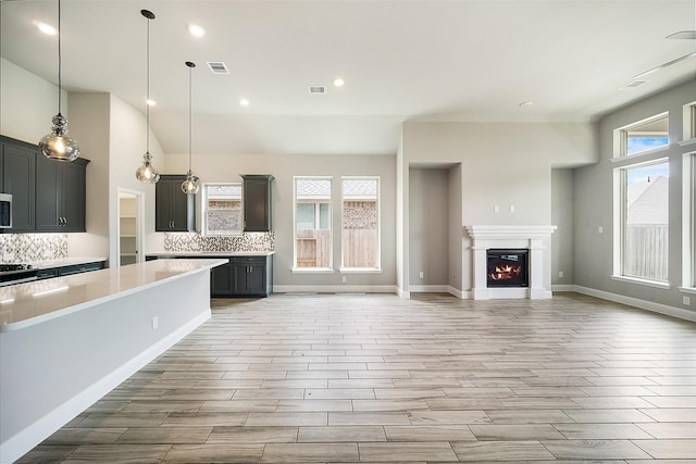 kitchen with a warm lit fireplace, visible vents, light countertops, and backsplash