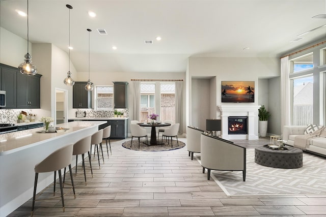 interior space with a warm lit fireplace, light countertops, visible vents, and decorative backsplash