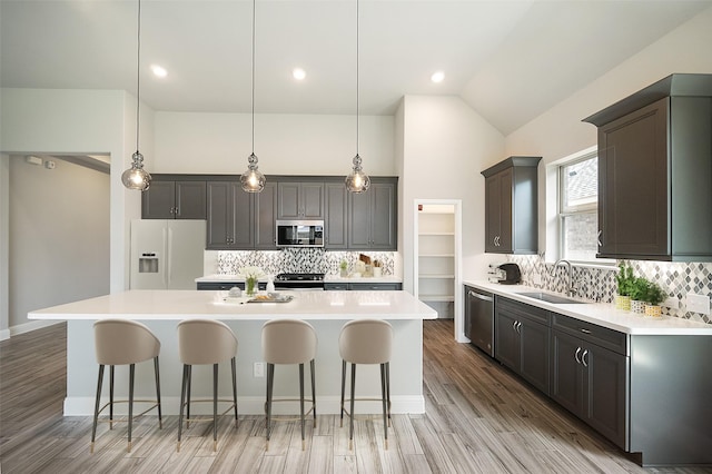 kitchen featuring stainless steel appliances, a breakfast bar area, a sink, and light countertops