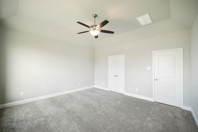 carpeted empty room with ceiling fan and a tray ceiling