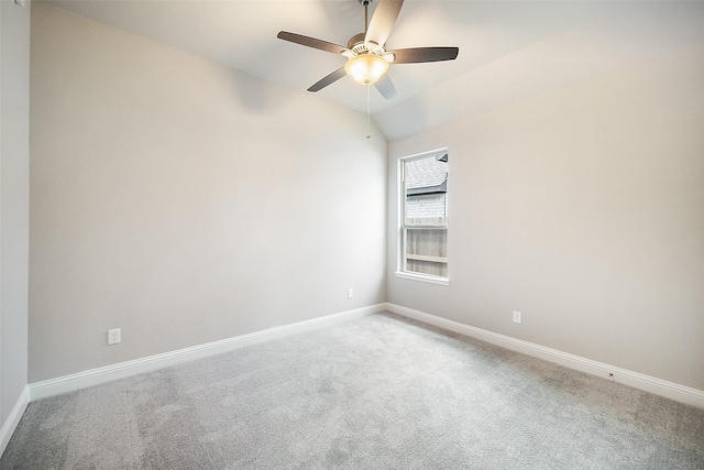 carpeted spare room with ceiling fan, vaulted ceiling, and baseboards