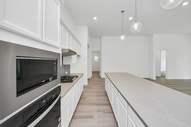 17733 Gold Saddle Ln, Magnolia, TX 77354 - kitchen featuring oven, stainless steel gas cooktop, light wood-type flooring, recessed lighting, and white cabinets