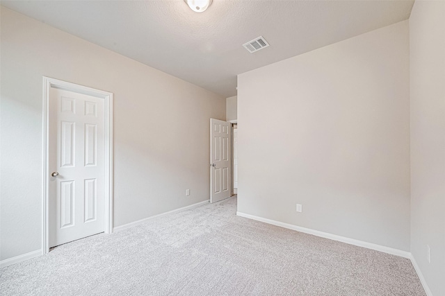 empty room with light colored carpet and a textured ceiling