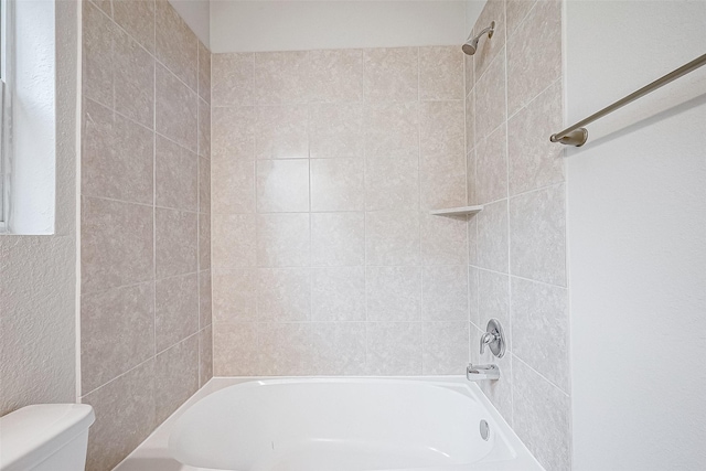 bathroom featuring tiled shower / bath and toilet