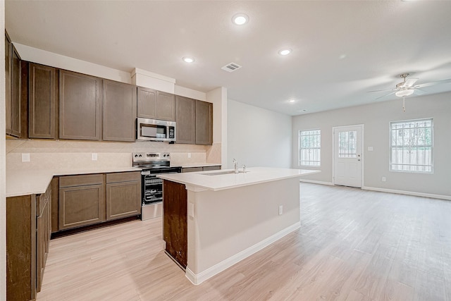 kitchen featuring stainless steel appliances, sink, ceiling fan, light hardwood / wood-style floors, and backsplash