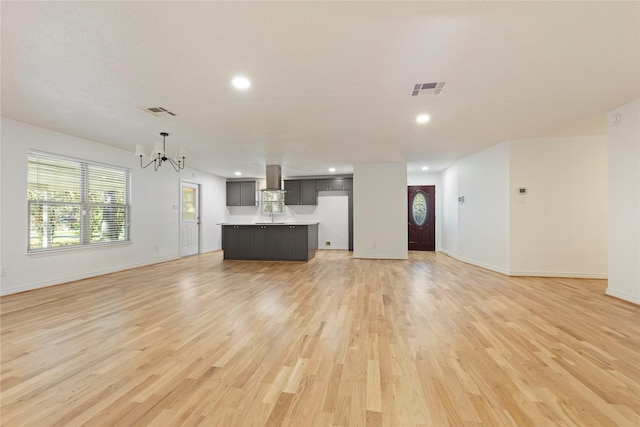 unfurnished living room with a notable chandelier and light wood-type flooring