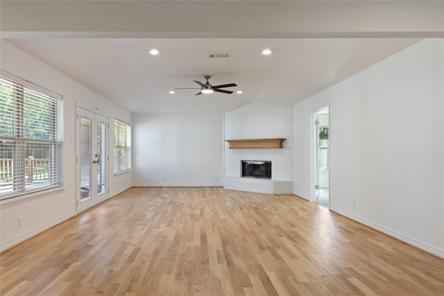 unfurnished living room featuring light wood-type flooring, a brick fireplace, ceiling fan, and lofted ceiling