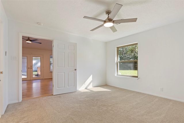 carpeted spare room with ceiling fan and french doors