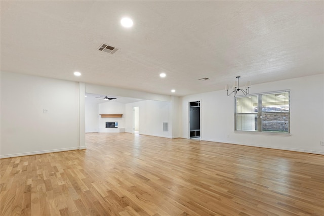 unfurnished living room featuring a textured ceiling, a notable chandelier, and light wood-type flooring