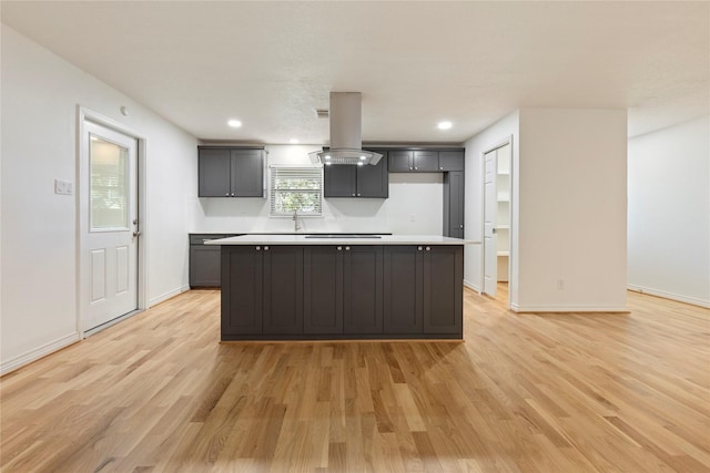 kitchen featuring a center island, island range hood, cooktop, and light wood-type flooring