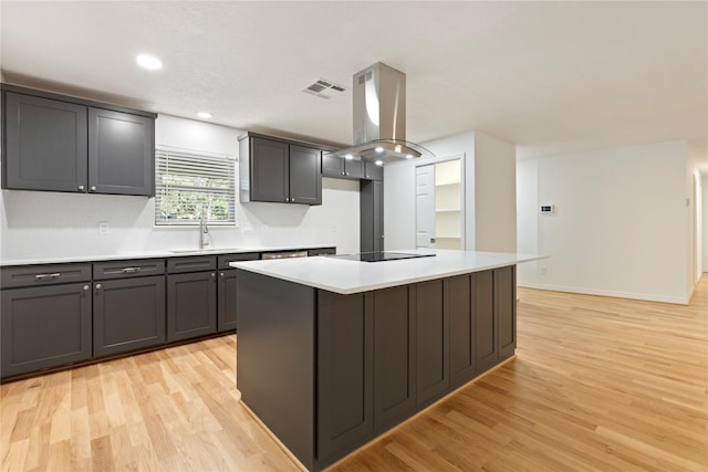 kitchen featuring a center island, black electric stovetop, sink, light hardwood / wood-style flooring, and island range hood