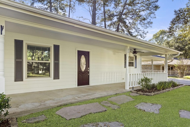 property entrance featuring a lawn, ceiling fan, and covered porch