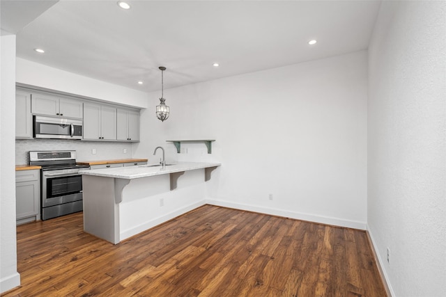 kitchen with dark hardwood / wood-style flooring, a breakfast bar, hanging light fixtures, and appliances with stainless steel finishes