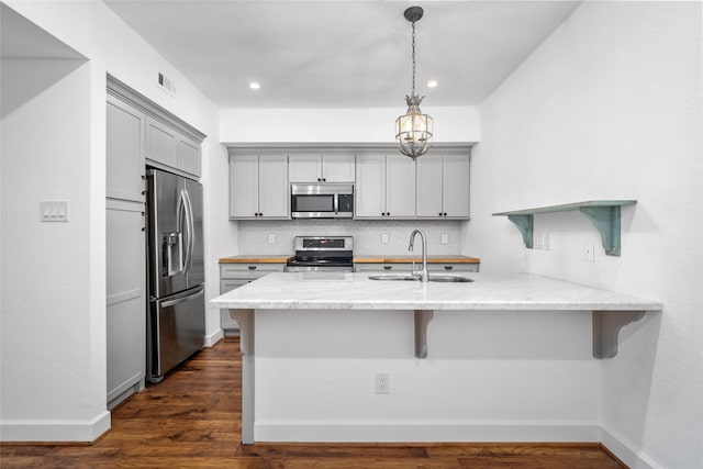 kitchen with a kitchen bar, gray cabinets, sink, and stainless steel appliances