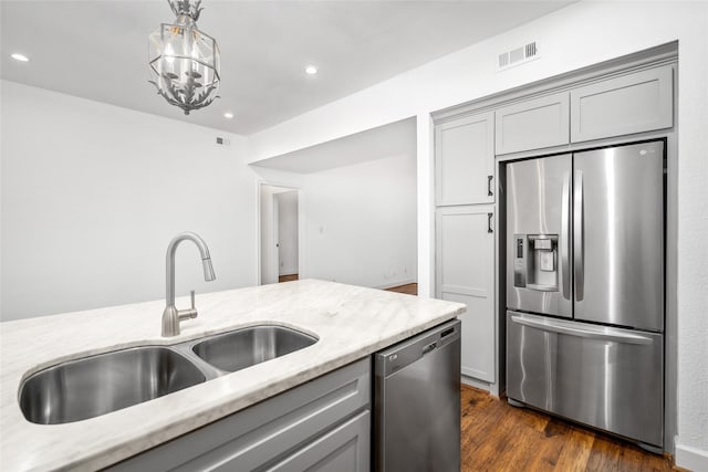 kitchen featuring light stone countertops, appliances with stainless steel finishes, hanging light fixtures, and sink