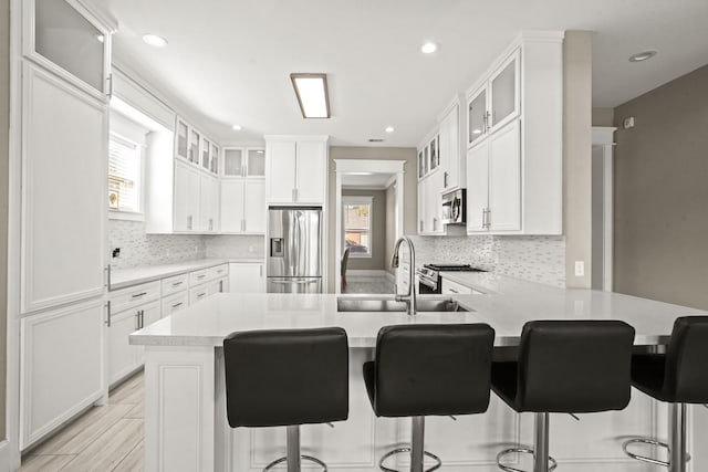 kitchen with kitchen peninsula, white cabinetry, sink, and stainless steel appliances