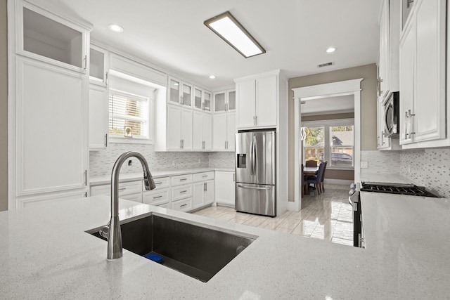 kitchen featuring light stone counters, sink, white cabinets, and stainless steel appliances