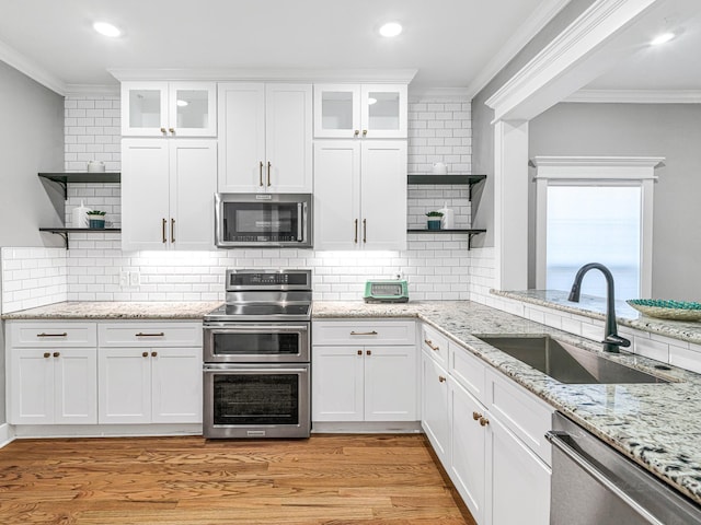 kitchen with tasteful backsplash, sink, white cabinetry, and appliances with stainless steel finishes