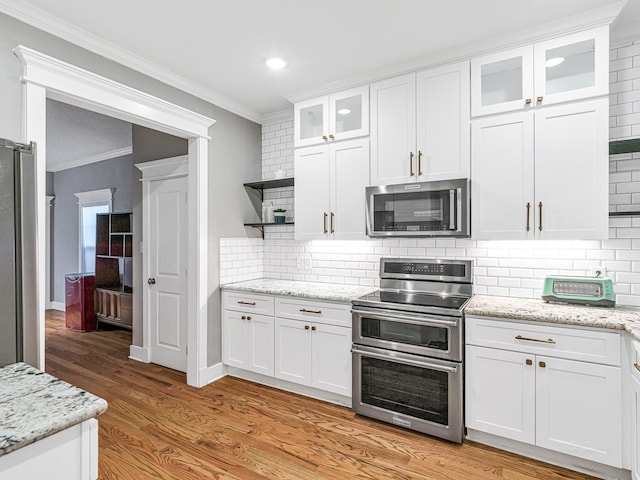 kitchen featuring white cabinetry, backsplash, stainless steel appliances, crown molding, and light wood-type flooring