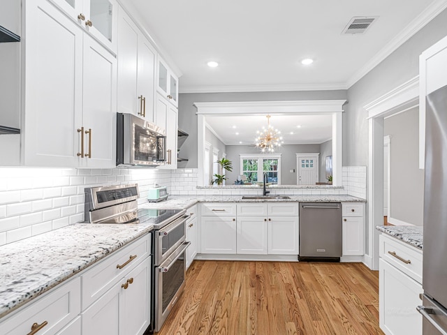 kitchen with tasteful backsplash, appliances with stainless steel finishes, sink, and white cabinets