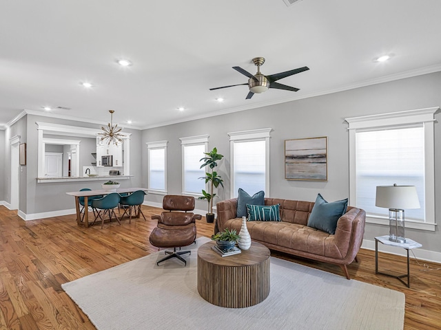 living room featuring crown molding, ceiling fan with notable chandelier, and light hardwood / wood-style floors