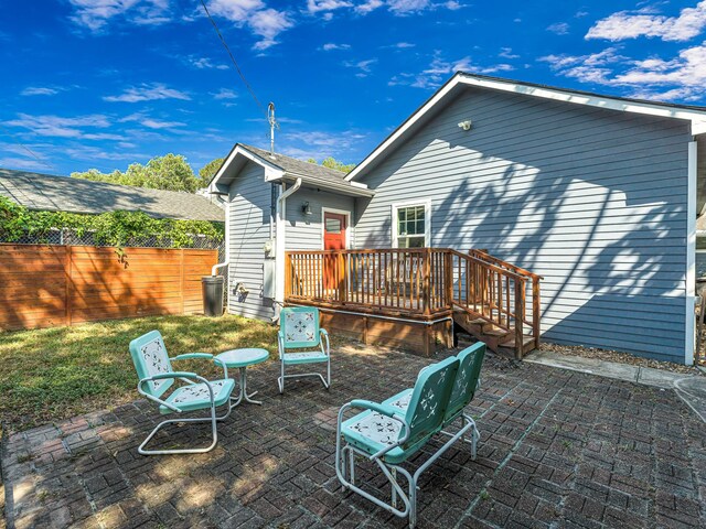 back of house with a wooden deck and a patio