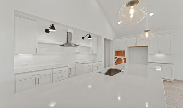 kitchen with ventilation hood, vaulted ceiling, sink, pendant lighting, and white cabinetry