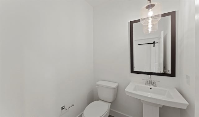 bathroom featuring baseboards, a sink, and toilet