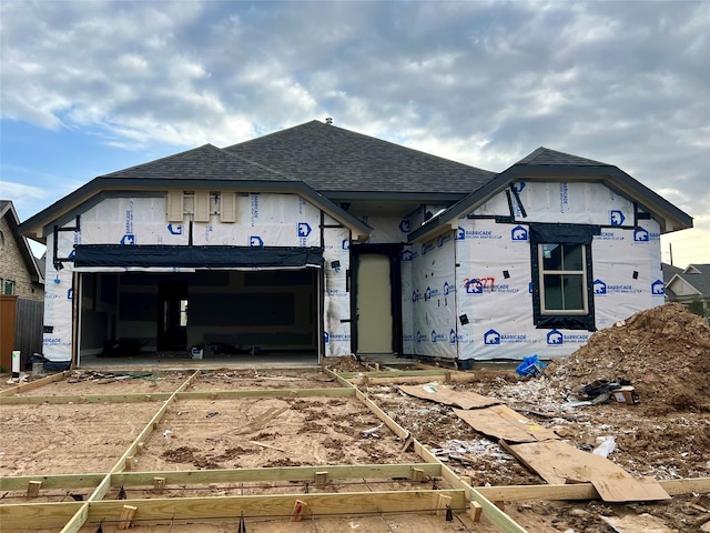 property under construction featuring a shingled roof and an attached garage