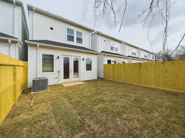 rear view of property with french doors, a yard, and central AC