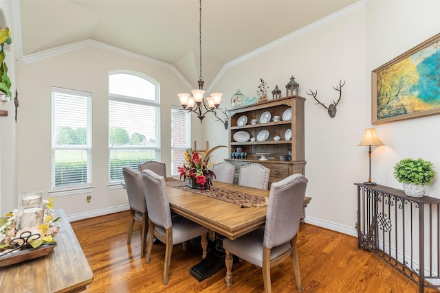 dining space with hardwood / wood-style flooring, a notable chandelier, lofted ceiling, and ornamental molding