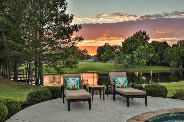 patio terrace at dusk with a water view and a yard